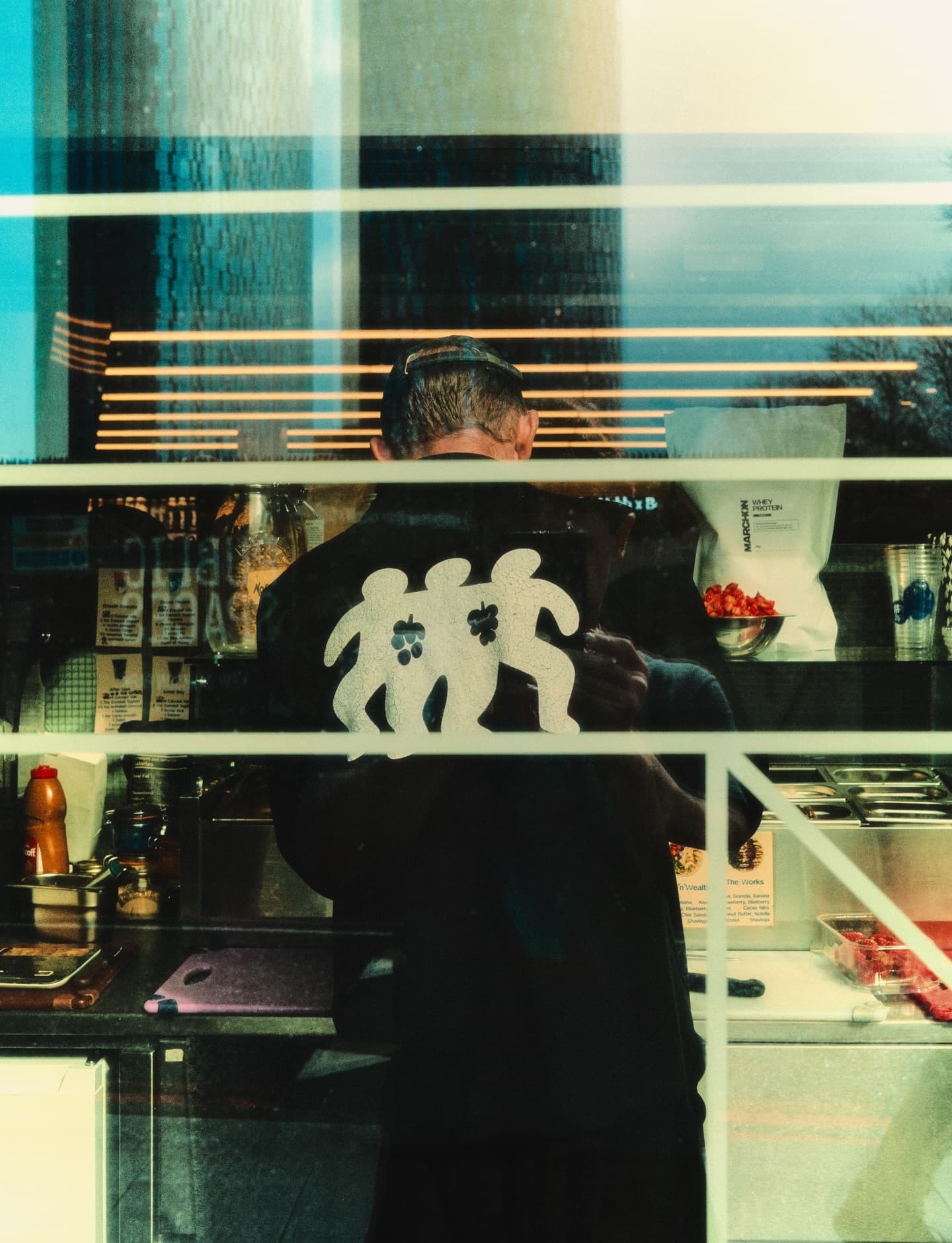 A Berry Boys tee seen through the store window, Manchester skyline reflected