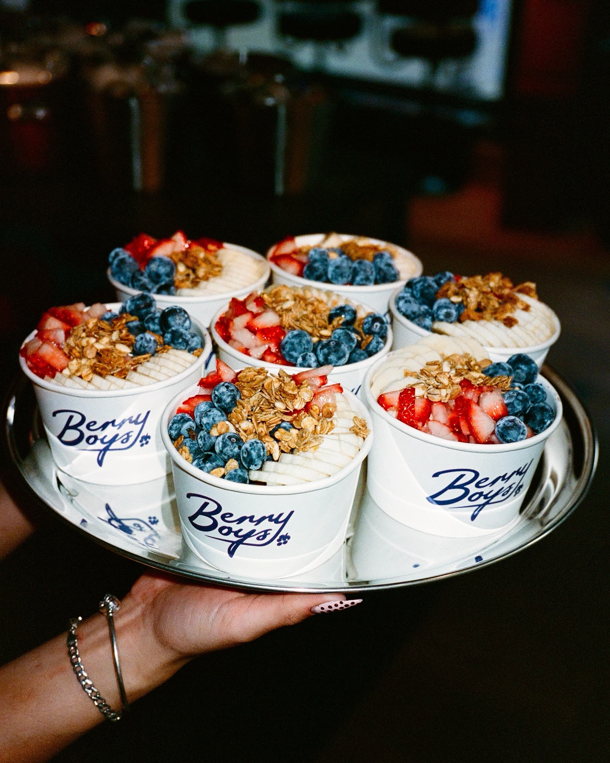 A tray of Berry Boys bowls topped with strawberries, blueberries and granola